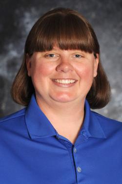 Image of a head shot of a woman with bangs wearing a bright blue shirt in front of a gray background